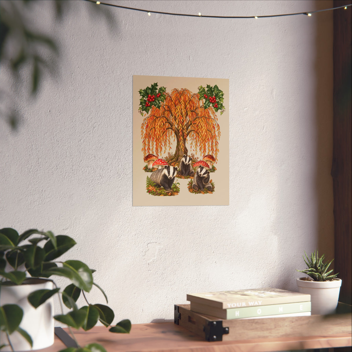 A vertical art print featuring a whimsical autumn tree with orange leaves, red mushrooms, and green holly, displayed on a textured white wall above a wooden shelf with books and plants.