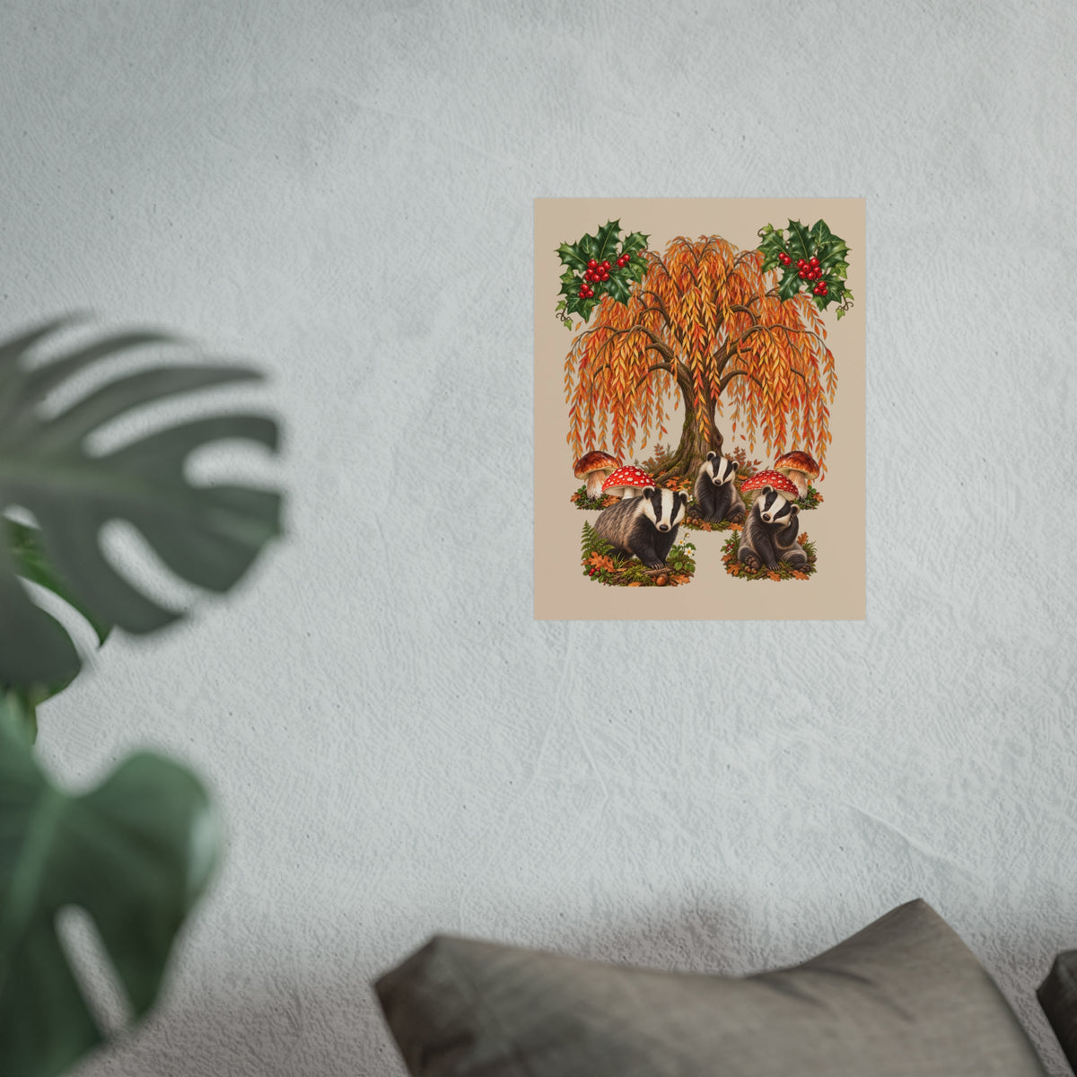 A vertical art print depicting two badgers under a weeping willow tree with red berries, displayed on a textured light gray wall with a blurred green plant in the foreground.