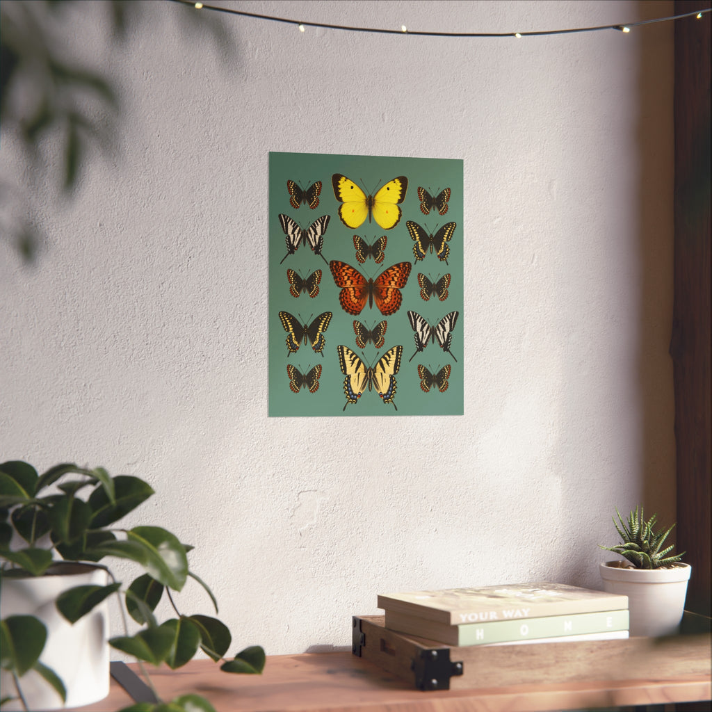 A vertical art print featuring various colorful butterflies on a muted green background, displayed on a textured white wall in a styled room setting with a wooden shelf, books, and potted plants.