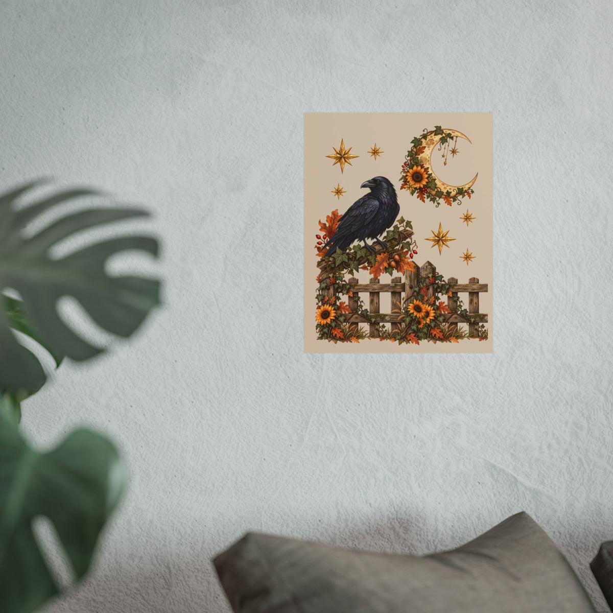 A vertical art print featuring a black raven perched on a wooden fence decorated with orange sunflowers and a crescent moon wreath, displayed on a textured light gray wall with a blurred green plant in the foreground.