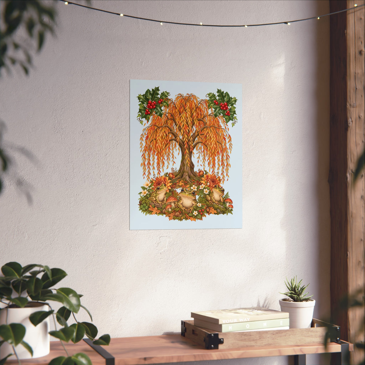 A vertical art print featuring a whimsical autumn tree with orange and gold leaves, red berries, and acorns on a light blue background, displayed on a textured white wall above a wooden console table with plants.