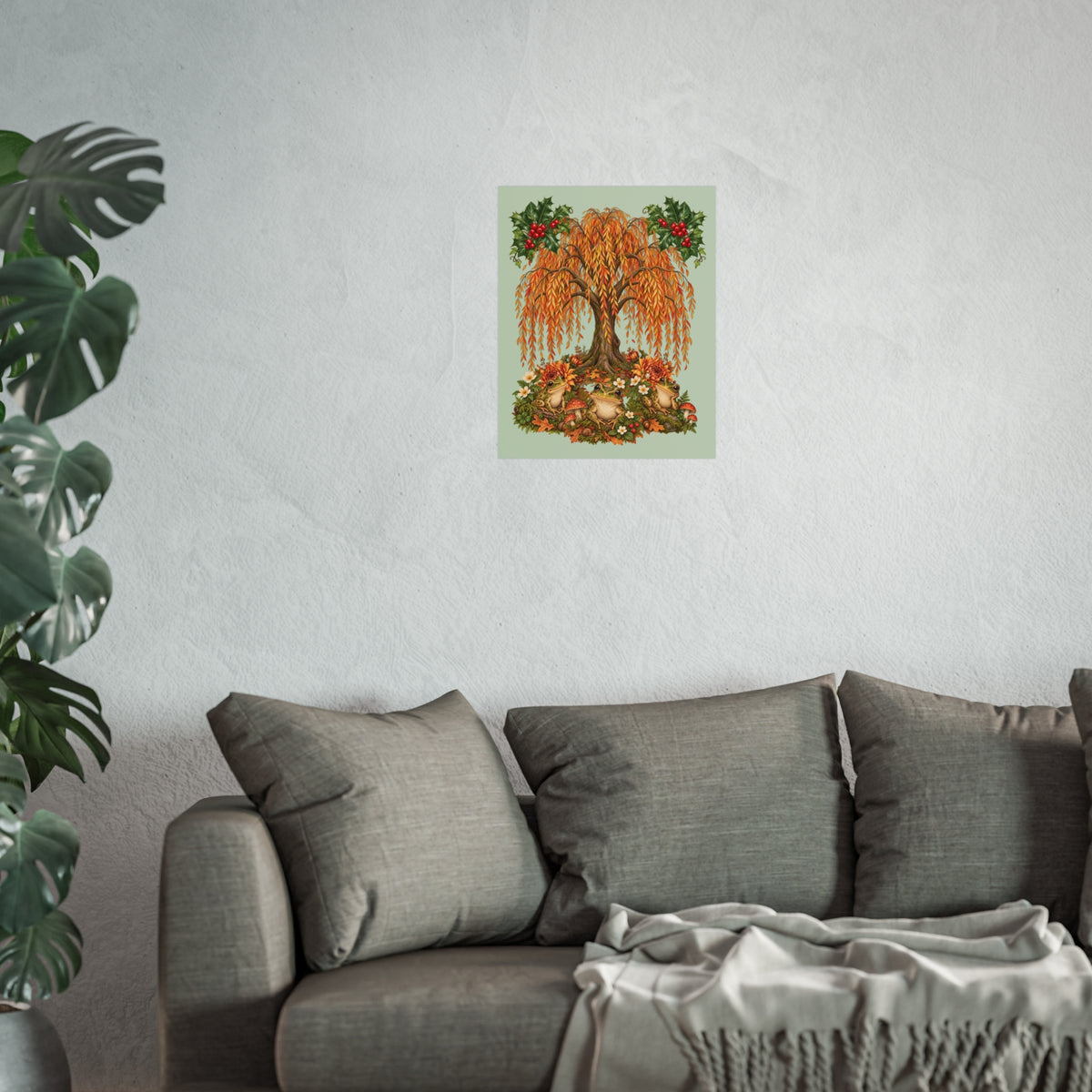 A framed wall art print featuring an autumn weeping tree with orange leaves and red berries, displayed above a gray sofa in a living room setting with a potted plant on the left.