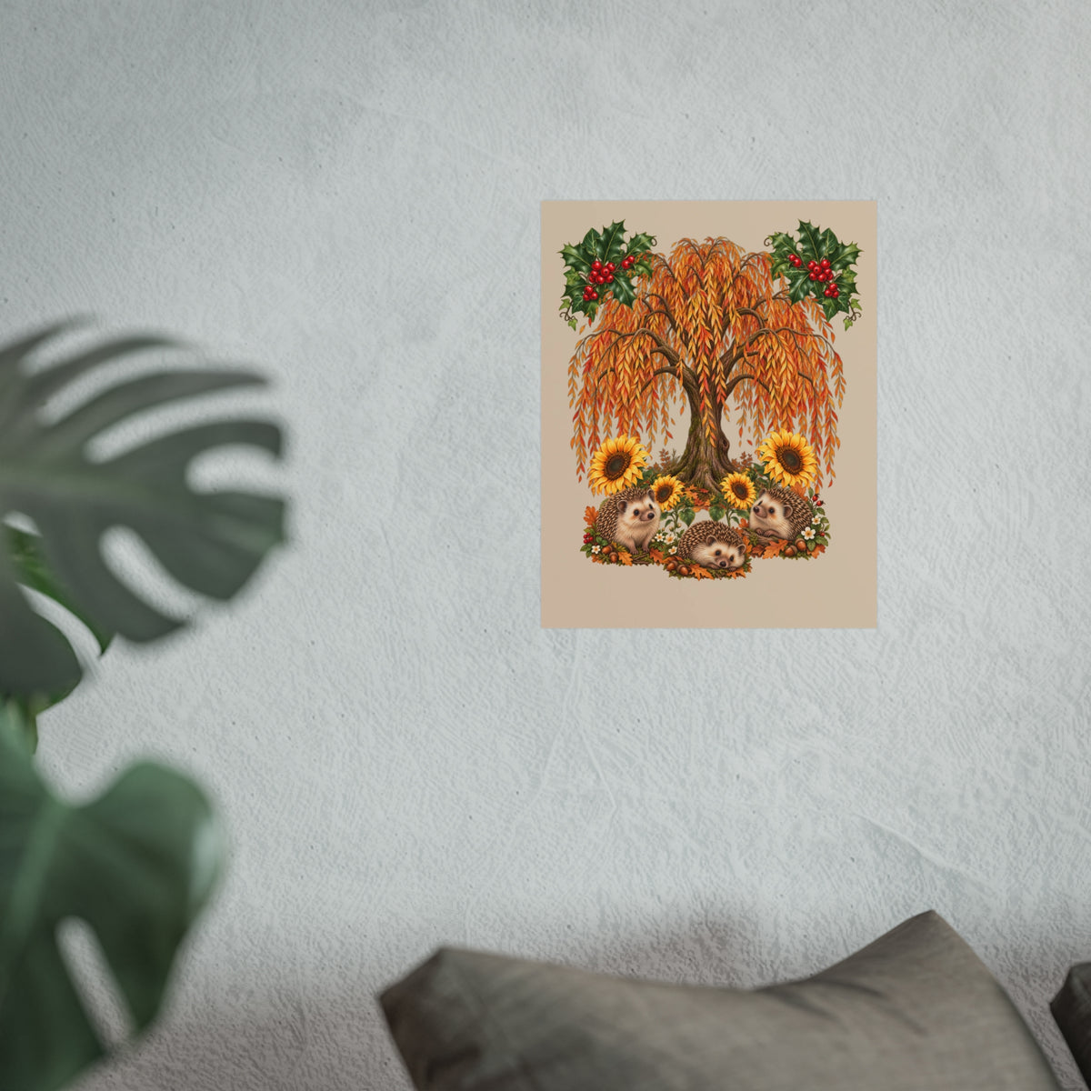 A vertical art print featuring an autumn willow tree with golden-orange leaves, sunflowers, hedgehogs, and red berries, displayed on a textured light gray wall with a blurred green plant in the foreground.