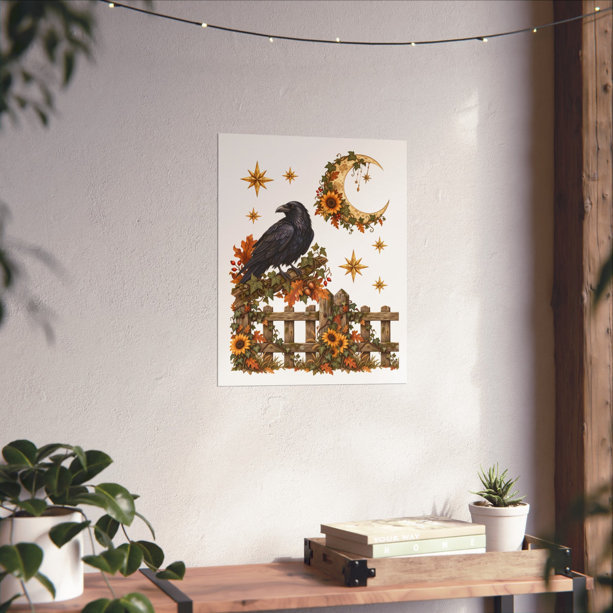 A vertical art print featuring a black raven perched on a rustic fence decorated with autumn flowers, sunflowers, and a crescent moon, displayed on a textured white wall above a wooden shelf with plants.